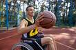 Young guy athlete having disability in wheelchair having basketball training