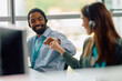 © Drazen - Happy African American call center agent fist bumping with his colleague while working in  office.