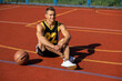 Handsome basketball player sitting on outdoor court