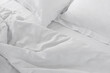 white satin crumpled bed linen on an unmade bed