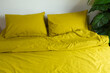 bright yellow crumpled bed linen on an unmade bed