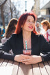 Beautiful happy woman with long red hair enjoying cocktail in a street cafe