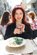 Beautiful happy woman with long red hair enjoying cocktail in a street cafe