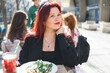 Millennial woman eating italian pasta at restaurant on the street in spring. Concept of Italian gastronomy and travel. Stylish woman with red hair