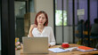 © apichat - A woman is sitting at a desk with a laptop and a cup of coffee. She is wearing glasses and she is deep in thought