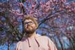 Man allergic enjoying after treatment from seasonal allergy at spring. Portrait of happy bearded man smiling in front of blossom tree at springtime. Spring blooming and allergy concept. Copy space