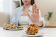 © Pormezz - Diet food loss weight concept, Hand of woman pushing fast food away and avoid to eat fried chicken to control cholesterol and sugar.
