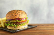 Burger with delicious patty and french fries on wooden table, space for text