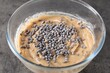 Raw dough with chocolate chips in bowl on grey table, closeup