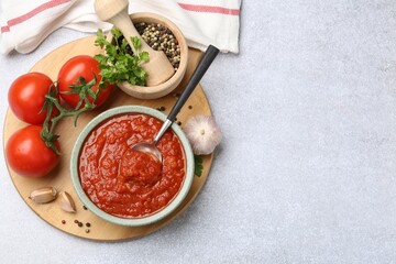 Wall Mural - Homemade tomato sauce in bowl, spoon and fresh ingredients on light grey table, flat lay. Space for text