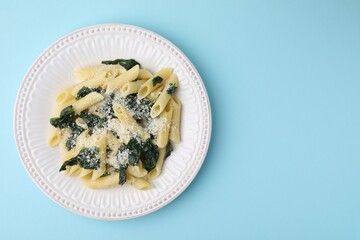 Wall Mural - Tasty pasta with spinach and cheese on light blue table, top view. Space for text
