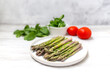 Asparagus on a plate on the table with tomato and salad. Healthy menu concept.  