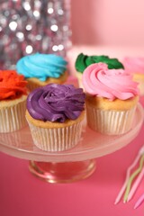 Wall Mural - Delicious cupcakes with bright cream on pink table, closeup