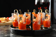 Tasty canapes with shrimps, tomatoes and sauce in shot glasses on black marble table, closeup