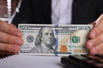 Wall Mural - Money exchange. Man holding dollar banknotes at table, closeup