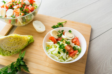 Wall Mural - fresh vegetable salad, cabbage, tomatoes in a bowl on a wooden table