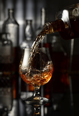 Wall Mural - Pouring brandy from a bottle into a glass.