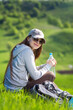 Young hiking woman taking a rest at green hill for rehydration