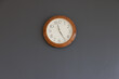 A plastic clock on grey on concrete wall.