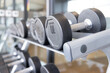A row of dumbbells on steel rack in fitness gym.