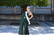 Pretty young woman winner of a beauty pageant dressed in a green sequined dress. Young woman wears diamond crown and winner's sash and poses for photo. Fashion and beauty concept.