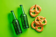 Beer bottles and pretzels on green background