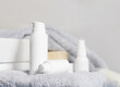 White one pump cosmetic bottles on grey folded towel near basin in bathroom, mockup