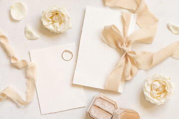 Wall Mural - Cards tied with a beige silk ribbon on white table top view, copy space, wedding stationery mockup