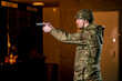 In a professional shooting range a military man in ammunition takes aim from a cleaned pistol