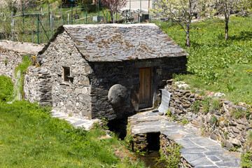 Wall Mural - Traditional small stone water mill on a bright sunny spring day next to stream with green vegetation in Tormaleo village Asturias