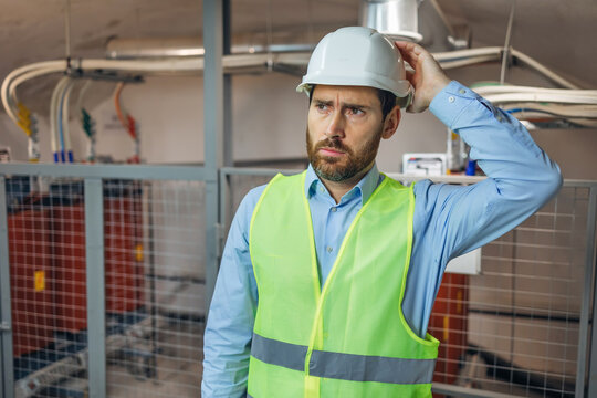 Handsome worker man wearing uniform and helmet on a plant looks clueless and confused expression. Doubt concept.