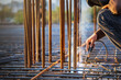 A welder welds a steel frame from reinforcement for reinforced concrete structures at a construction site.