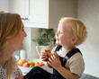 Mother With Young Son At Home In Kitchen Eating Cookie