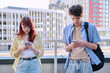 Teenage friends guy and girl using smartphones, urban outdoor
