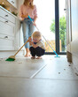 Mother With Young Son At Home In Kitchen Helping With Housework Sweeping Floor