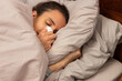 © Serhii - Young woman with cold blows her nose in tissue while lying in bed; adult female with virus or flu blows nose into tissue and rests in comfortable cosy bed; ill sick lady lies in bed and tries to sleep