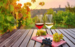 Two glasses of red and white wine and bunches of grapes on the table standing in the vineyard. 