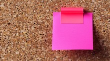   A Pink Paper With A Pink Sticky Note On A Red Cork Floor, A Red Paper Pinned Nearby