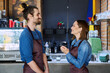 Colleagues business partners young man and woman in aprons talking at workplace