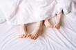 The legs of an adult and a child stick out from a white blanket.