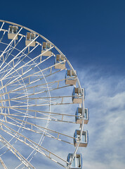 Wall Mural - A majestic Ferris wheel stands tall against a cloudy blue sky. Amusement Park. Vertical photo.