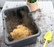 Ingredients for the soil of home potted plants, peat, earth, sand, perlite, vermiculite, coconut. A mixture for planting plants in a pot florist's gloved hands are mixing in a container