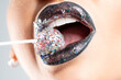 Close up view of beautiful woman lips with a festive lollipop.