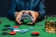 A wealthy man drinking brandy and playing poker with the excitement in a casino.