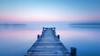 A long wooden pier extends into the calm blue lake at dawn