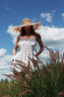 Young sexy beautiful woman in a straw hat stands in the garden against the background of the sky.	