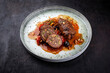Traditional slow cooked German wagyu beef roulades with olives and pine nuts served in spicy red wine sauce as close-up in a Nordic design plate with copy space