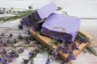 Lavender soap with flowers lying in a soap dish on a vintage wooden board. 