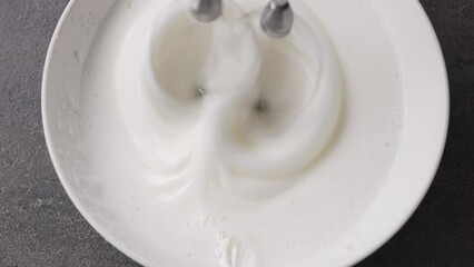 Sticker - Chef whips raw egg whites with powdered sugar in a white bowl with a mixer, top view. Close-up of food, zoom in