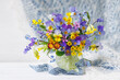 Spring still life with flowers, bouquet with pansies, forget-me-nots, primroses, forget-me-nots, muscari and phlox in a vase on the table, a beautiful postcard.